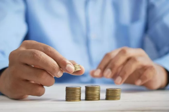 A man counts coins on a wooden table